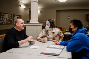 Minnesota college students working as Direct Care Professionals with ACR Homes enjoy time doing graduate school mentorship program requirements while talking with a man with disabilities who lives at ACR Homes.