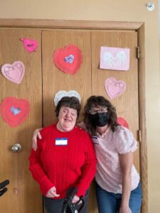 ACR Homes valentines day party. Group Home manager and person with disabilities posing together at party.
