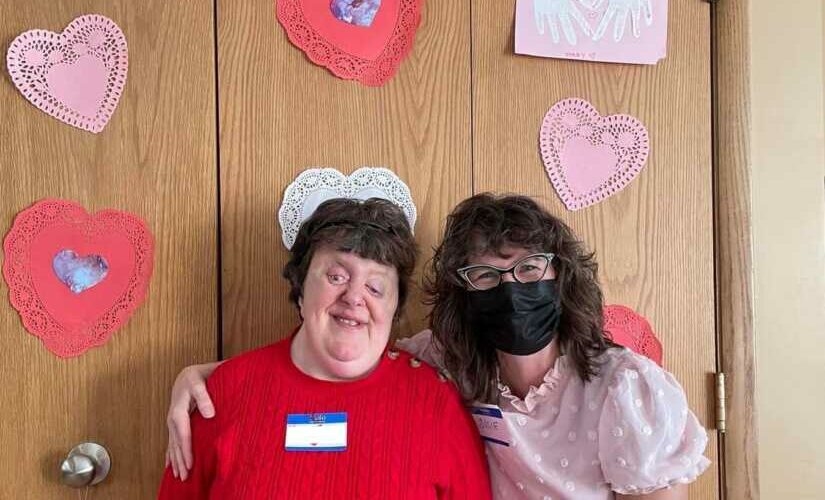 ACR Homes valentines day party. Group Home manager and person with disabilities posing together at party.