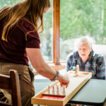 Direct Care Professional plays chess with senior citizen who is receiving memory care at ACR's sister company Arthur's Senior Care